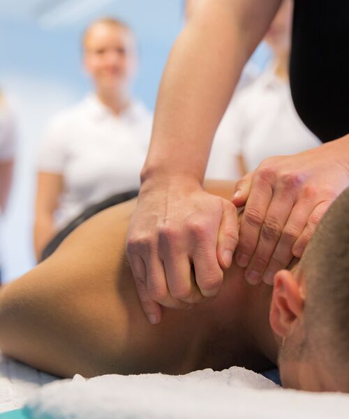 Ein Mann auf einer Liege wird an der Schulter massiert