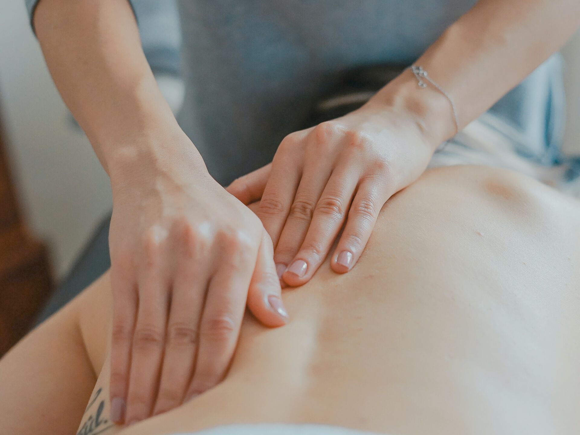Nahaufnahme einer Rückenmassage, bei der zwei Hände sanft auf dem Rücken einer liegenden Person arbeiten.