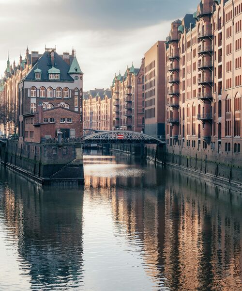 Blick auf die historische Speicherstadt in Hamburg mit Backsteinhäusern, Wasserkanal und Brücke bei weichem Tageslicht.